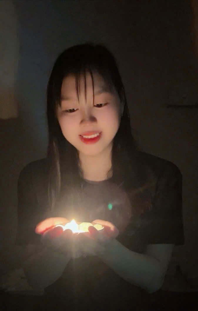 A child holding a lit candle
Description automatically generated