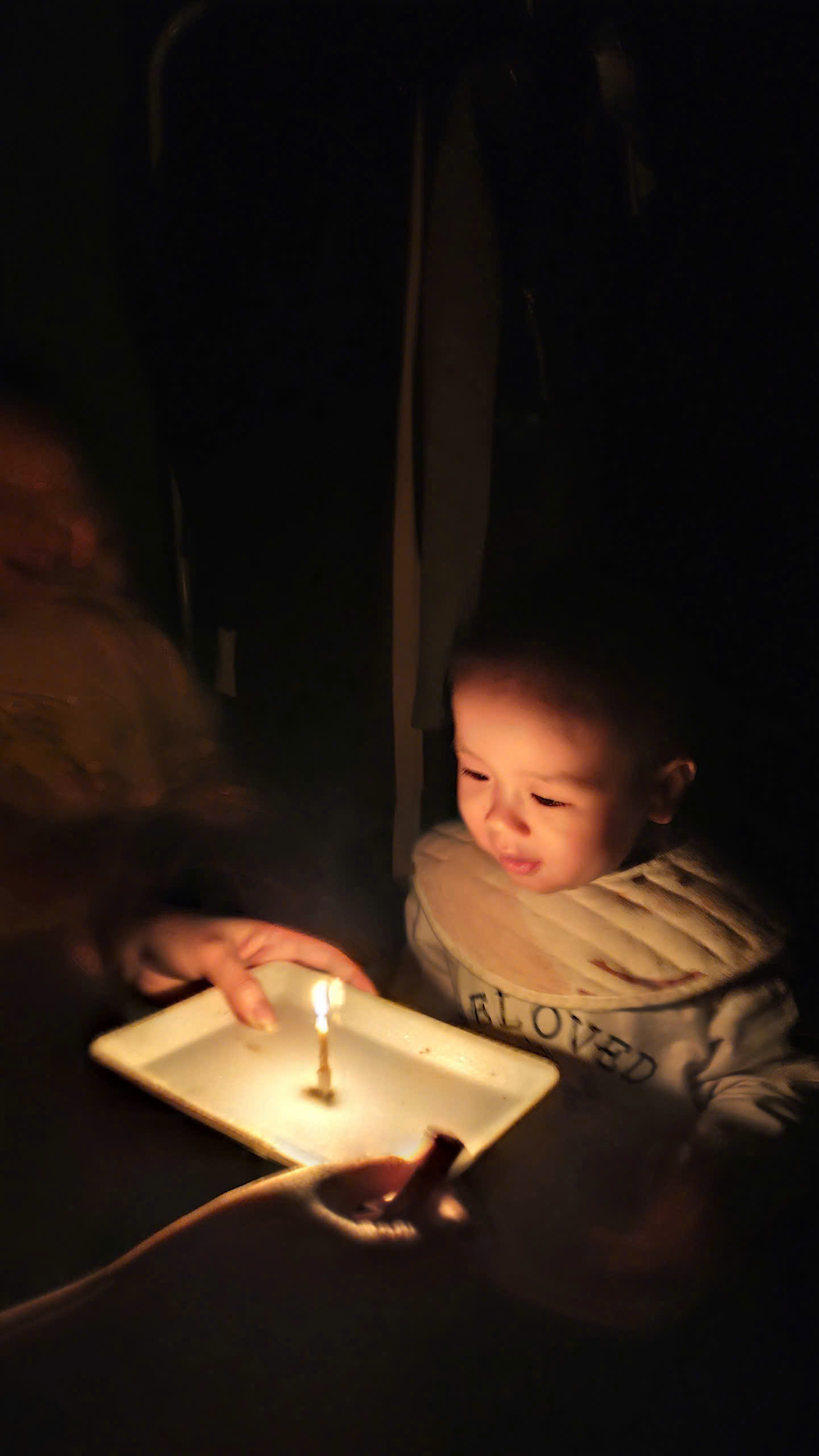 A baby with a lit candle on a plate
Description automatically generated