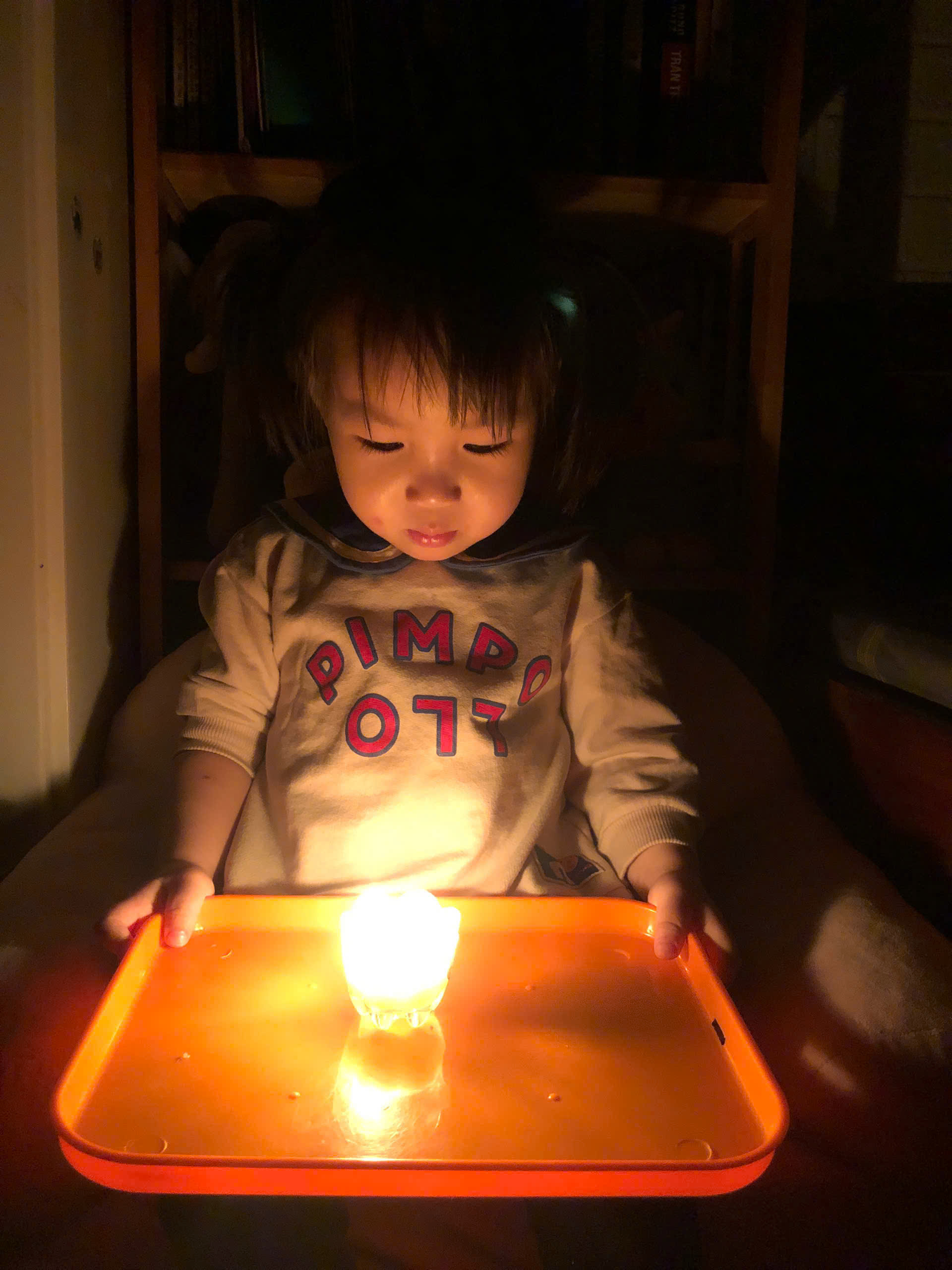 A child sitting in a chair with a light on a tray
Description automatically generated