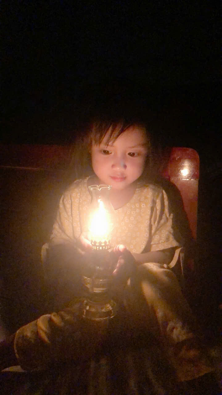 A child holding a lit candle
Description automatically generated