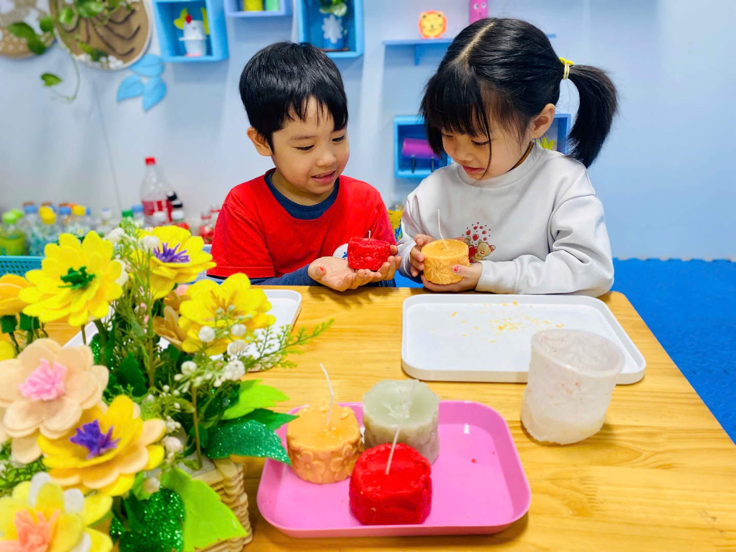 A child and child sitting at a table with flowers and candles
AI-generated content may be incorrect.