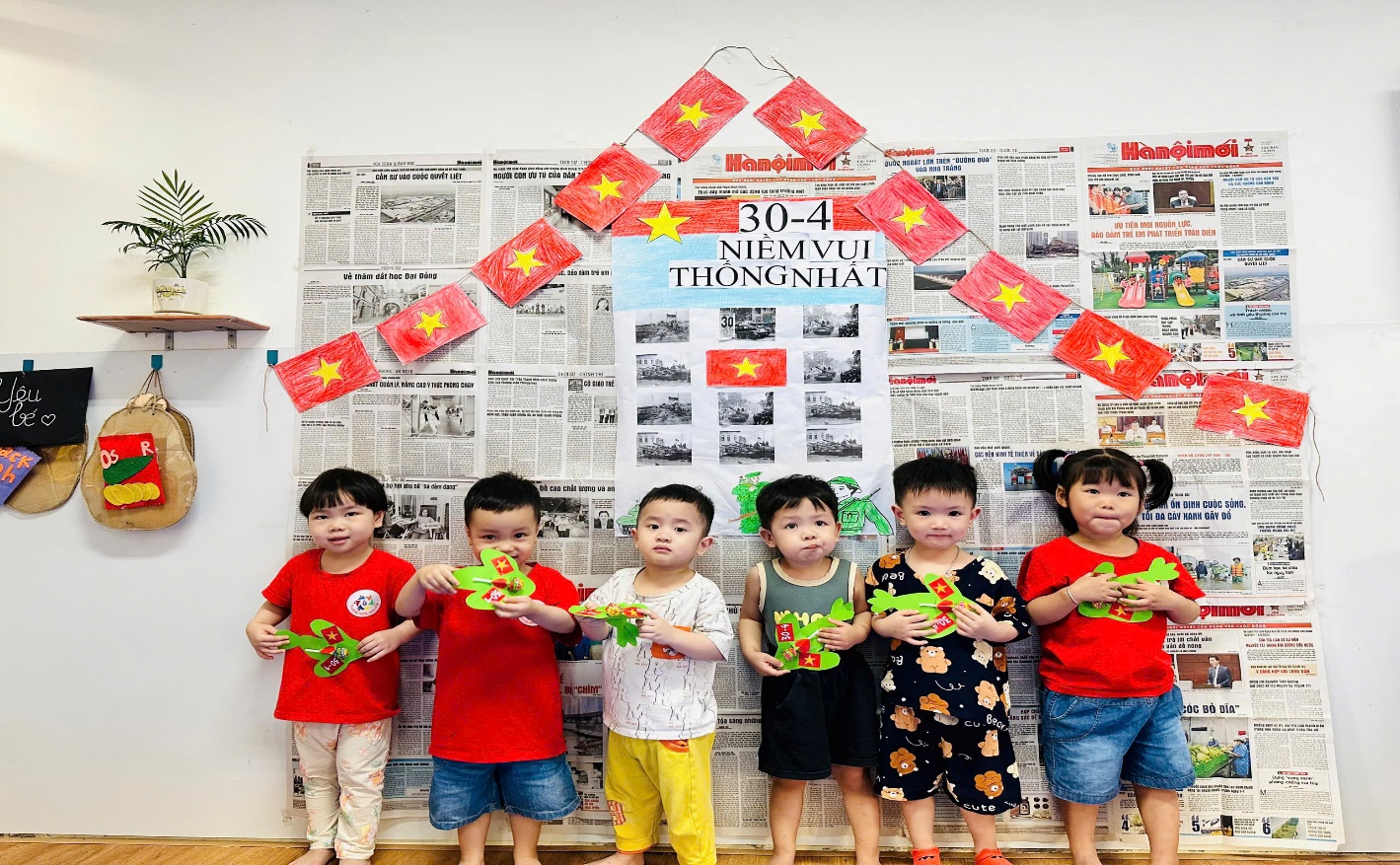 A group of children standing in front of a wall with flags
Description automatically generated