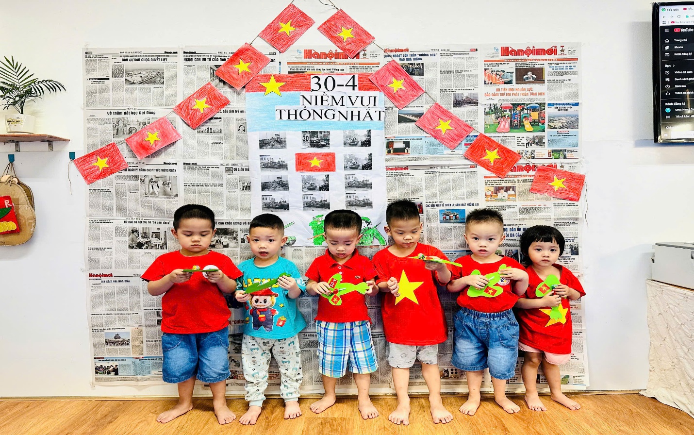 A group of children standing in front of a wall with newspaper
Description automatically generated