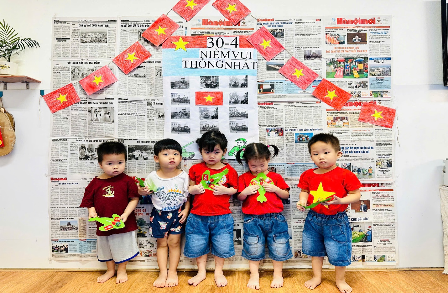 A group of children standing in front of a wall with newspaper
Description automatically generated