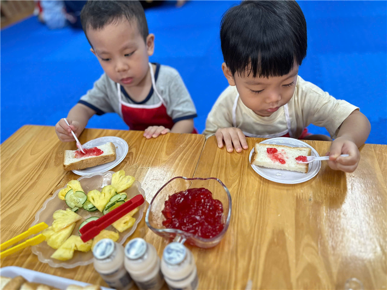 Two boys sitting at a table eating food
Description automatically generated