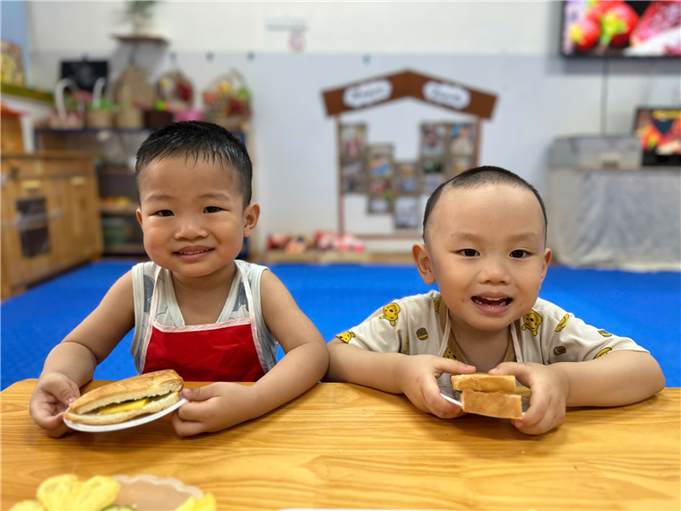 Two young boys sitting at a table with food on plates
Description automatically generated